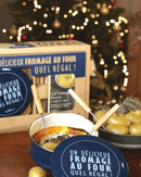 Coffret Cuiseur Fromage Fondu de Cookut avec fromage, pommes de terre et décorations de Noël en arrière-plan.