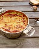 Sauteuse inox Casteline amovible avec gratin de pommes de terre dorées sur une table en bois.