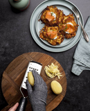 Gant anti-coupures Microplane utilisé pour râper des pommes de terre près de plats garnis de saumon.