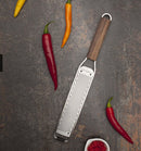Râpe zesteur Microplane avec manche en bois et lames en acier inoxydable, entourée de piments colorés.