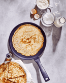 Crêpière Energy Beka avec crêpes dorées sur une surface grise, ingrédients à côté pour une cuisson parfaite.