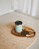 Mug isotherme 350 ml en inox recyclé Qwetch sur une table en bois avec des grains de café
