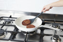 Utilisation d'un retourneur silicone pour retourner des galettes dans une poêle sur un cuisinière.